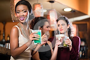 Group of women drinking cocktails in bar