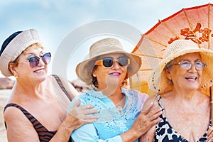 Group of women friends aged smiling and posing for a photo in summer outdoor leisure activity together in friendship. Coloruful