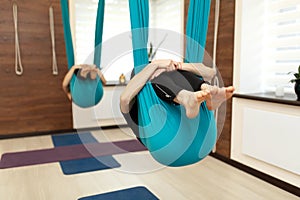 A group of women are hanging in a fetal position in a hammock. fly yoga class in the gym. Fit and wellness lifestyle