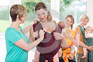 Group of women learning how to use baby slings for mother-child