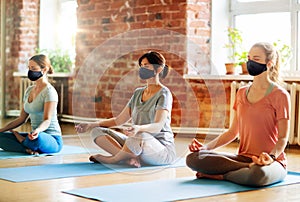 group of women in masks doing yoga at studio