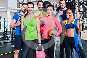 Group of women and men in gym posing at fitness training