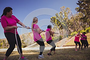 Group of women playing tug of war during obstacle course training
