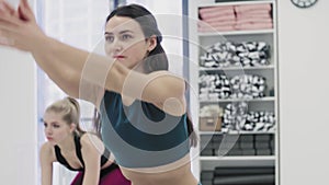 Group of women practicing yoga in commodious light studio