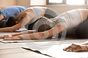 Group of women practicing yoga lesson, Balasana pose close up