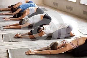 Group of women practicing yoga lesson doing Balasana exercise photo