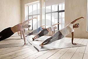 Group of women practicing yoga lesson doing Side Plank pose