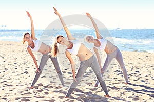 Group of women practising yoga on the beach