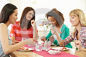 Group Of Women Sitting Around Table Eating Dessert