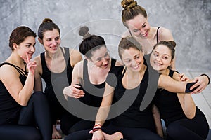 Group of women sitting and relaxing after a long yoga class and taking selfie