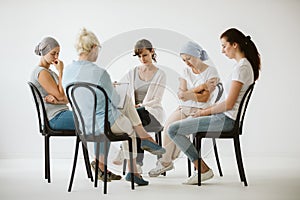 Group of women sitting together during psychotherapy with senior counselor