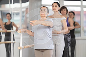 Group of women stand in first position at barre