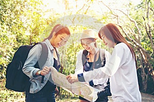 Group women traveler with backpack adventure holding map to find directions and walking relax in the jungle