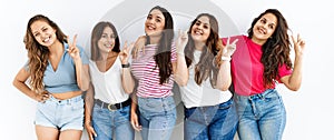 Group of women wearing casual clothes standing over isolated background smiling looking to the camera showing fingers doing