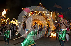 A group of Wood Tappers perform in front of the Temple of the Sacred Tooth Relic during the Esala Perahera in Kandy, Sri Lanka.