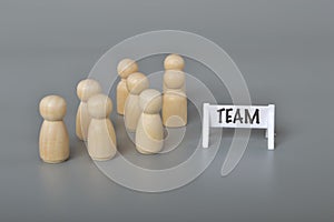 A group of wooden figure with text TEAM. unity and teamwork in corporate workplace concept
