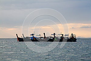 Group of wooden long tail boat floating on sea with raining cloud background. Transportation and Nature