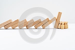 Group of Wooden Peg Dolls Resisting and Stopping Domino Effect Falls photo