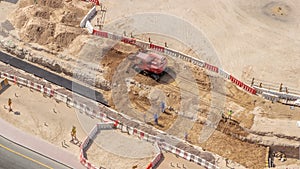 Group of worker and red excavator diging water drainage at construction site aerial timelapse.