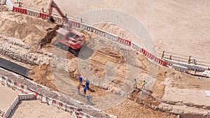 Group of worker and red excavator diging water drainage at construction site aerial timelapse.