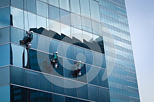 Group of workers cleaning windows service on high rise building