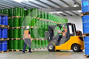 group of workers in the logistics industry work in a warehouse with chemicals - lifting truck