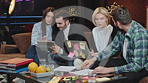 Group of workers from a office modern studio working all together like a team while sitting on the sofa using notebook