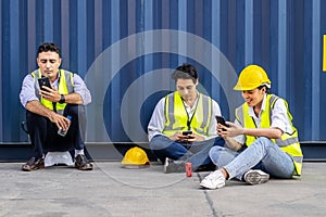 Group of workers playing, online chatting or browsing on mobile phone while taking a break at construction site