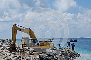 Group of workers using excavator at construction site on shore of ocean