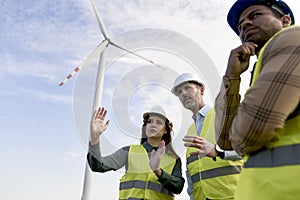 Group of workes standing on wind turbine field