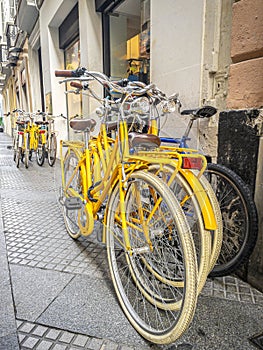 Group of yellow bikes for rent outside a bicycle rental shop