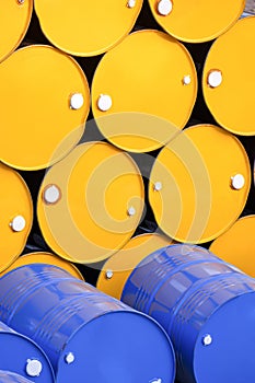 Group of yellow and blue 200 liter oil drums stacked in vertical frame