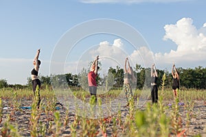 group yoga performing sun salutations outdoors