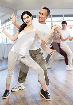 Group of young active people dancing twist or rock and roll dance in dance hall