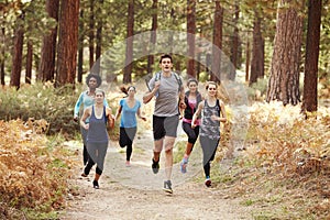 Group of young adult friends running in a forest