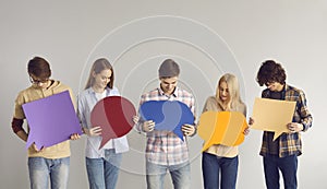 Group of young adult men and women holding multicolored empty mockup speech bubbles