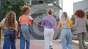 Group of young adult women walking and jumping together. Teenage females moving on slow motion. Affectionate cool girls