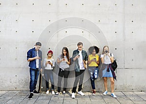Group of young adults outdoors using smartphones together and ch