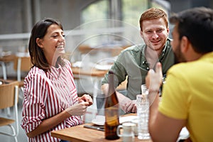 Group of young adults talking and smiling in restaurant. Conversation, friendship, lesure