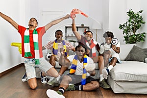 Group of young african american friends watching and supporting soccer match at home