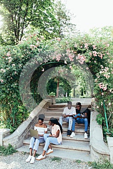 Group of young african people are studying together in university. Students outdoors sitting on stairs