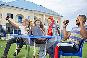 Group of young Africans sitting together celebrating the success of their online startup business