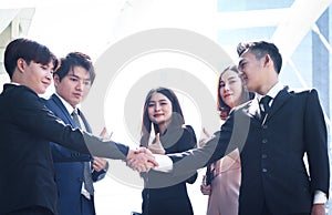 Group of young Asian achievement successful businesspeople shaking hands after sign contract, corporate group giving thumbs up and