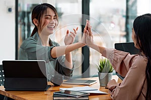 Group of young asian business people giving coworker high five in office celebrating achievement and success. business