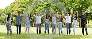 Happy young group of friends with arms raised together at the park