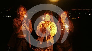 Group of young Asian friends are having fun playing fireworks during a summer camping vacation. concept of freedom, leisure, trave