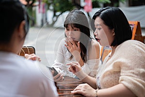 A group of young Asian girl friends are enjoying talking chitchat at a coffee shop in the city photo