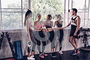 Group of young asian people in sportswear talking after a workout in gym