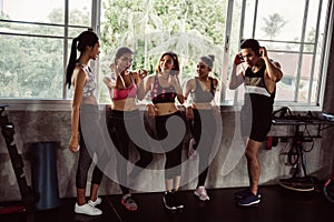 Group of young asian people in sportswear talking after a workout in gym