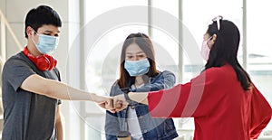 Group of young Asian travelers wearing face mask standing in the airport terminal greeting with a fist bump for a new normal